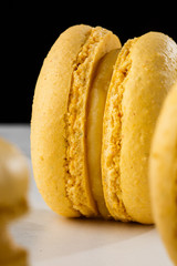 French macaroons isolated. Selective focus. Beautiful yellow macaroons on marble and dark background. Stylish arrangement sweet. Flat lay, top view. Macro photo.