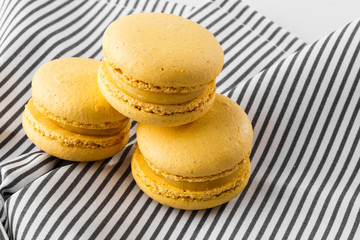 French macaroons isolated. Selective focus. Beautiful yellow macaroons on striped napkin background. Stylish arrangement sweet. Flat lay, top view. Macro photo.