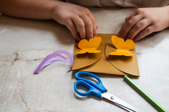 Crafts for children. A child makes a colorful paper greeting card. The child does crafts. Creative little boy with envelope and scissors.