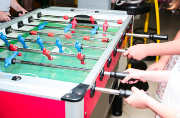 Detail of kid's hands playing the foosball table match. Soccer game, friends recreation