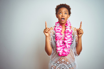 Young african american woman with afro hair wearing flower hawaiian lei over isolated background...