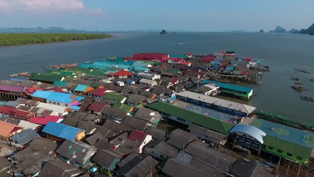 A high angle shot of the diverse colors of the roofs of a settlement surrounded by water  