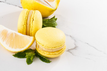 French macaroons isolated. Selective focus. Beautiful yellow macaroons with lemon and mint on marble background. Stylish arrangement sweet. Flat lay, top view. Macro photo. With copy space.