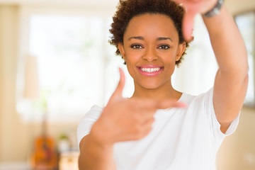 Young beautiful african american woman wearing casual white t-shirt smiling making frame with hands and fingers with happy face. Creativity and photography concept.