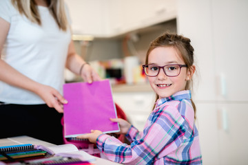 Mother helping her daughter in packing school bag.