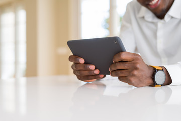 Close up of african business man using touchpad tablet, working sitting on a desk smiling