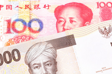 A gray two thousand Indonesian rupiah bank note with a red, one hundred Chinese yuan 