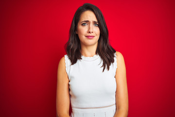 Young beautiful woman wearing white dress standing over red isolated background depressed and worry for distress, crying angry and afraid. Sad expression.