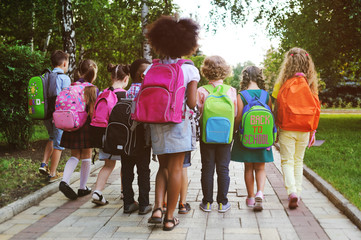 small schoolchildren with colorful school bags and backpacks run to school. Back to school, education, elementary school.