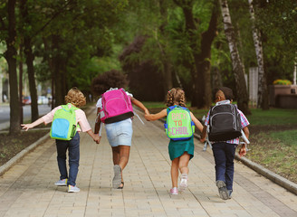 small schoolchildren with colorful school bags and backpacks run to school. Back to school,...