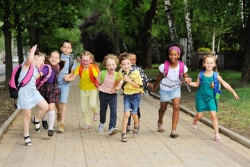 small schoolchildren with colorful school bags and backpacks run to school. Back to school, education, elementary school.