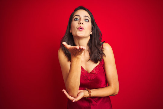 Young beautiful woman wearing sexy lingerie over red isolated background looking at the camera blowing a kiss with hand on air being lovely and sexy. Love expression.