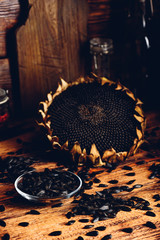 Roasted seeds on the glass saucer and dried sunflower over old wooden surface