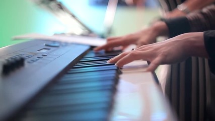Musician girl playing the synthesizer during the concert. The fingers of the girl press the keys of the synthesizer. Shooting close-up.