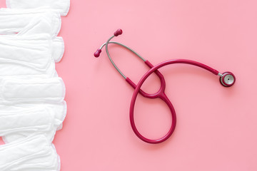 Gynaecologist and menstruation concept with stethoscope and sanitary pads on pink background top...