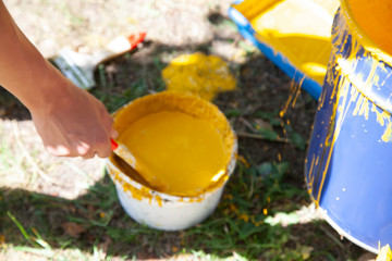 Paint brush. Man paints objects in the yard. Work with color. It's time to upgrade the garden.
