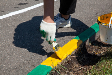 Paint brush. Man paints objects in the yard. Work with color. It's time to upgrade the garden.