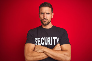 Young safeguard man wearing security uniform over red isolated background skeptic and nervous,...