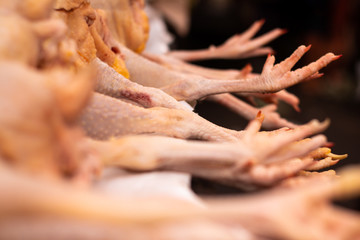 Dead hens on a table. Numerous legs together in the market. White meat for human consumption.