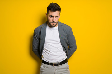 Fototapeta premium Young handsome man possing and modeling over yellow isolated background