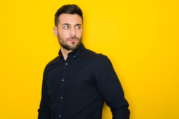 Fototapeta premium Young handsome man possing and modeling over yellow isolated background