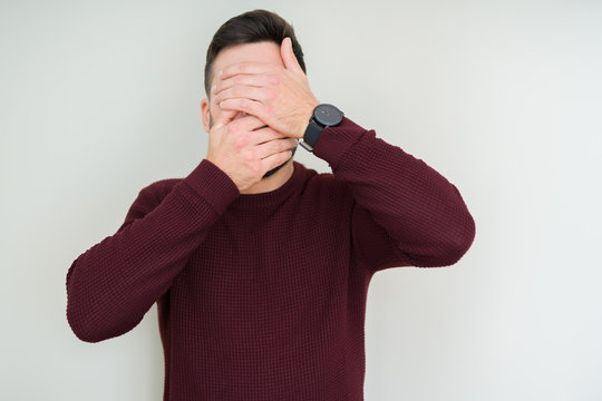 Young handsome man wearing a sweater over isolated background Covering eyes and mouth with hands, surprised and shocked. Hiding emotion