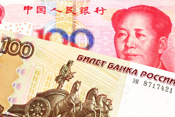 A close up image of a one hundred Russian ruble bank note close up with a red one hundred Chinese yuan bank note