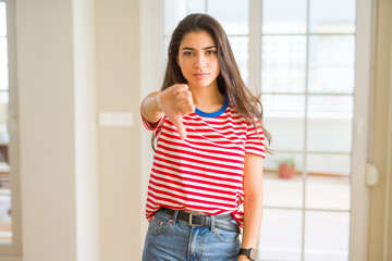 Young beautiful woman wearing casual t-shirt looking unhappy and angry showing rejection and negative with thumbs down gesture. Bad expression.