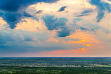 Fototapeta na wymiar Scenic sunset with clouds in sky in steppe