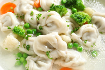 Tasty dumplings and vegetables in broth, closeup
