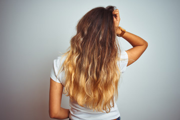 Fototapeta premium Young beautiful woman wearing casual white t-shirt over isolated background Backwards thinking about doubt with hand on head