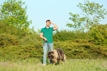Young man walking his Caucasian Shepherd dog in park