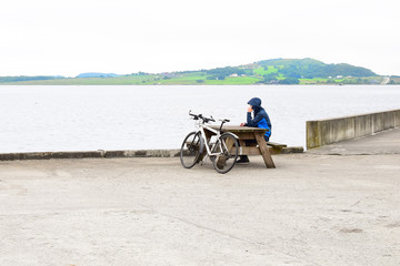 A man sits on the pier by the sea. Cyclist on holiday by the sea.