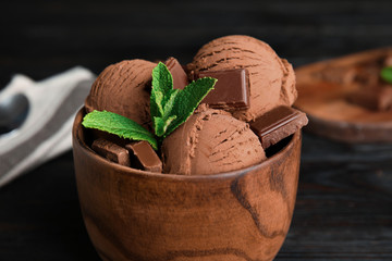 Wooden bowl of chocolate ice cream and mint on table, closeup