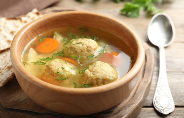 Bowl of Jewish matzoh balls soup on wooden table, closeup