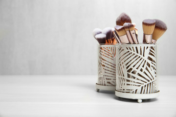 Organizers with professional makeup brushes on light table. Space for text
