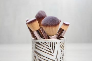 Organizer with professional makeup brushes against light background, closeup