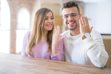 Young cheerful couple smiling happy showing wedding ring, celebrating engagement at home
