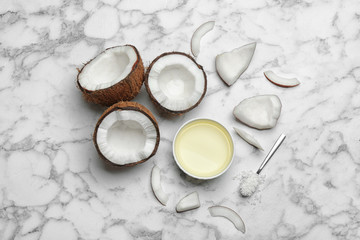 Fototapeta na wymiar Bowl of natural organic oil and coconuts on marble background, flat lay