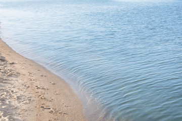 View of sea water and beach sand on sunny summer day