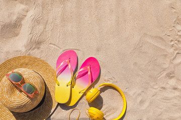 Different beach accessories on sand, top view with space for text. Summer vacation