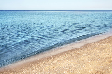 View of sea water and beach sand on sunny summer day