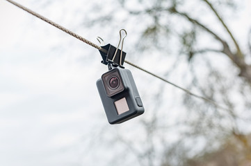 Drying waterproof action camera on the clip, against the sky.