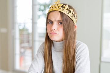 Beautiful young girl wearing a golden crown as a princess from fairytale skeptic and nervous, disapproving expression on face with crossed arms. Negative person.