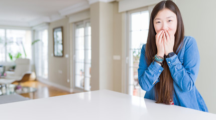 Young beautiful asian woman with long hair wearing denim jacket laughing and embarrassed giggle...