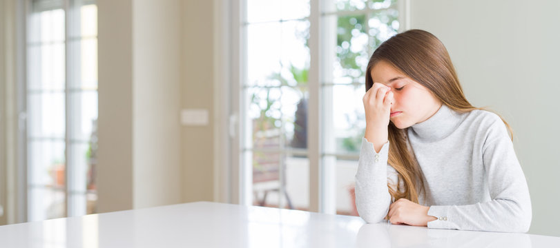Wide angle picture of beautiful young girl kid wearing casual sweater tired rubbing nose and eyes feeling fatigue and headache. Stress and frustration concept.