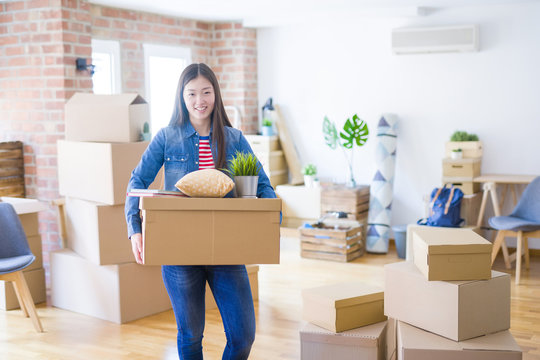 Beautiful asian young woman holding boxes, smiling happy moving to a new home