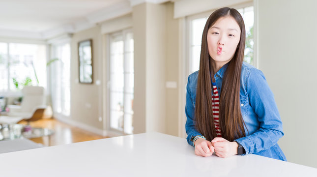 Young beautiful asian woman with long hair wearing denim jacket making fish face with lips, crazy and comical gesture. Funny expression.