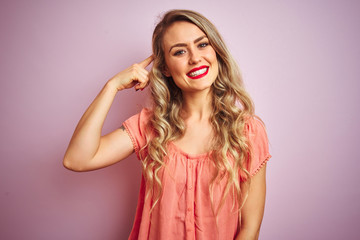 Fototapeta premium Young beautiful woman wearing t-shirt standing over pink isolated background Smiling pointing to head with one finger, great idea or thought, good memory