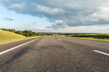 Modern asphalt road with road marking elements. Perspective view of a two-lane highway passing through a forest